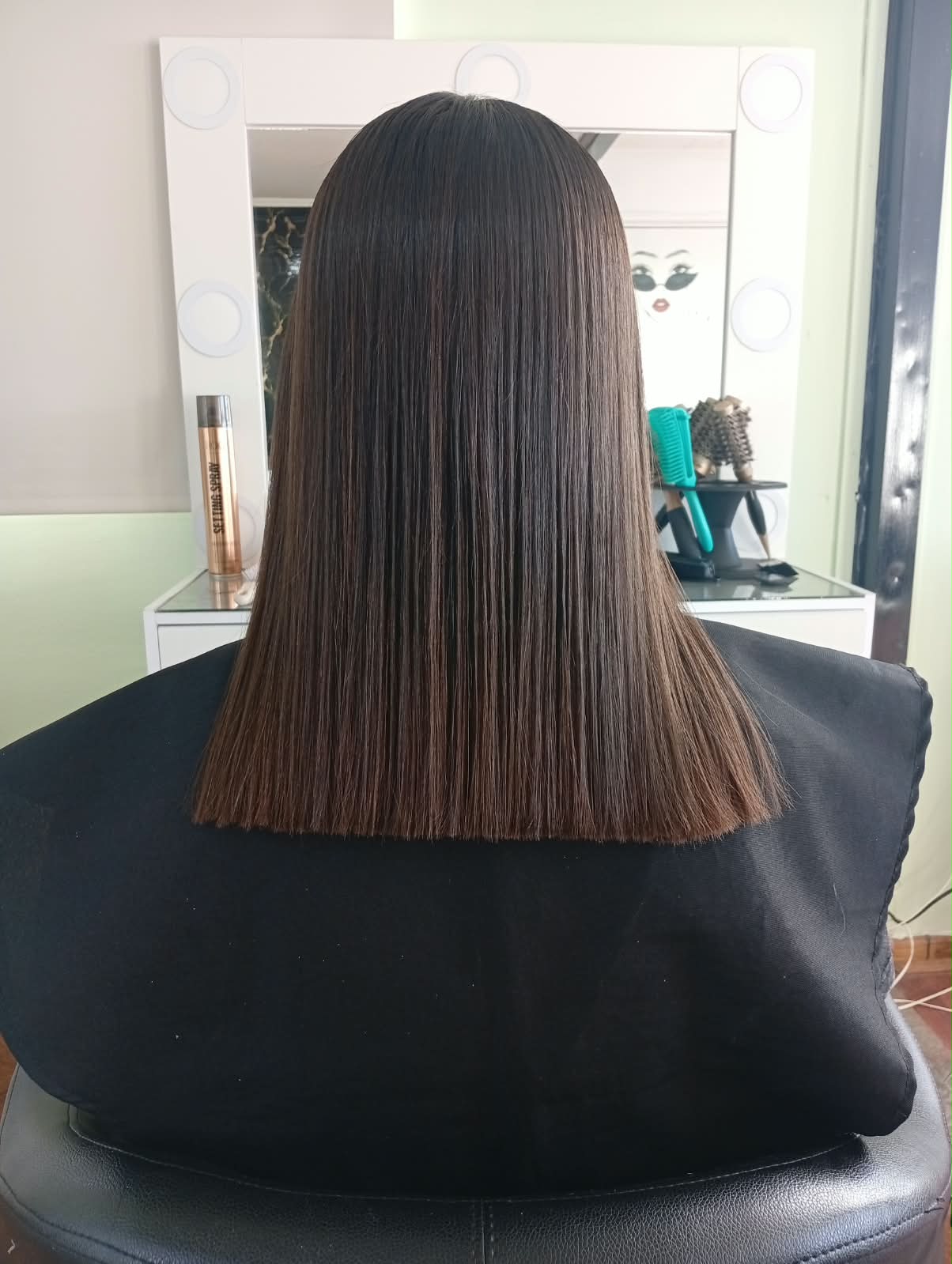 Corte recto a la altura de los hombros en cabello castaño liso, visto de espaldas frente al espejo